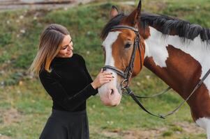 Portrait of young pretty cheerful woman with horse at summer photo