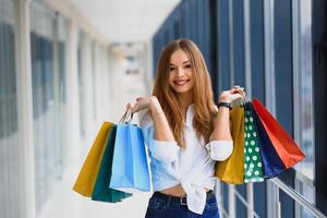 Beautiful girl with shopping bags is looking at camera and smiling while doing shopping in the mall photo