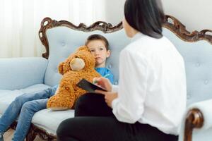 Female psychologist calming cute little boy in office photo