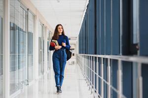 Portrait of a pretty female student with books and a backpack in the university hallway photo