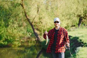 young fisherman fishes near the river. The concept of outdoor activities and fishing photo