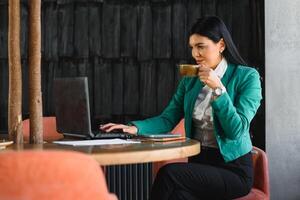 Cheerful attractive businesswoman drinking tea in her office photo