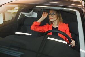 young woman looking in the rearview mirror of a car photo