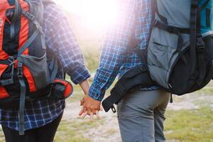 contento romántico Pareja hombre y mujer viajeros con mochila participación manos alpinismo viaje estilo de vida y relación amor concepto montañas paisaje en antecedentes foto