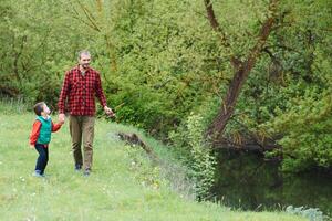 A father teaching his son how to fish on a river outside in summer sunshine photo