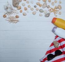 Beach accessories. Towel, flip-flops, starfish, boat and sunglasses on wooden background. Top view with copy space. Sunny toned photo