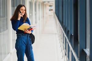 Portrait of a pretty female student with books and a backpack in the university hallway photo