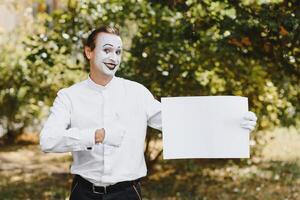 Your text here. Actors mimes holding empty white letter. Colorful portrait with green background. April fools day photo