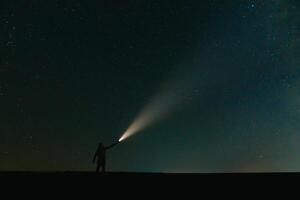 espalda ver de hombre con cabeza Linterna en pie en verde herboso campo debajo hermosa oscuro azul verano estrellado cielo. noche fotografía, belleza de naturaleza concepto. amplio panorama, Copiar espacio antecedentes. foto