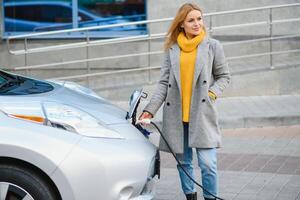 mujer cargando electro coche a el eléctrico gas estación. foto