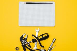 Tools top view on yellow background. Plier, open wrenches, screwdrivers and staple gun flat lay with copy space photo