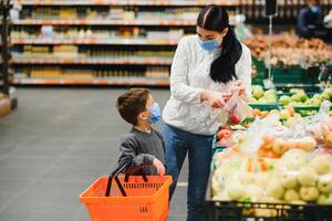 Mother and her son wearing protective face mask shop at a supermarket during the coronavirus epidemic. photo