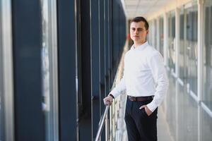 Handsome young businessman near window in office photo