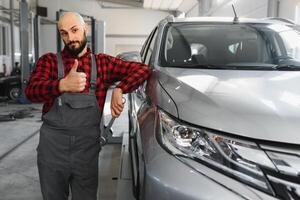 masculino mecánico trabajando a un reparar tienda y participación herramientas foto