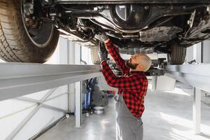 Mechanic working under car at the repair garage. Auto mechanic working in garage. Repair service. photo