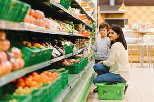 Young mother with her little baby boy at the supermarket. Healthy eating concept photo