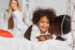 Family laying down together in a bed photo