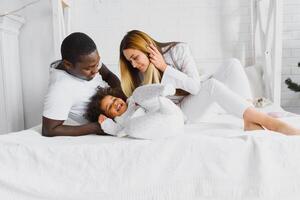 Family laying down together in a bed photo