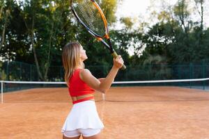 Woman playing tennis at the court and holding racket photo