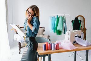 Working on new collection. New order. Female fashion designer works on the new clothes in the workshop. photo