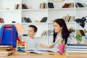 Portrait of handsome boy at workplace with his tutor sitting near by and telling something photo