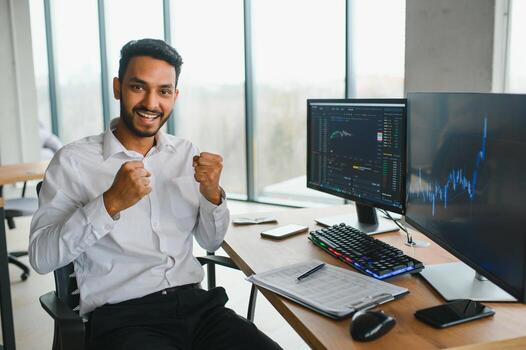 Young indian business man trader looking at computer screen with trading charts reflecting in eyeglasses watching stock trading market financial data growth concept, close up. photo