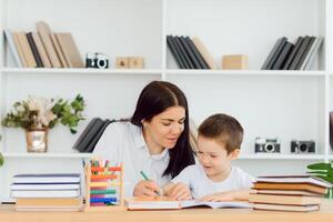 tutor deals with the preschooler with a laptop, a real home interior, the concept of childhood and learning photo