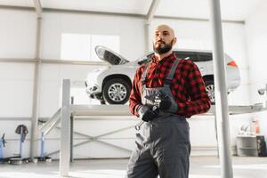 Mechanic working and holding wrench of service order for maintaining car at the repair shop photo