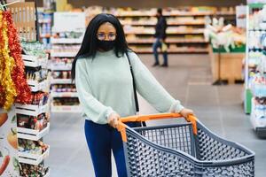 African american woman with shopping cart trolley in the supermarket store photo