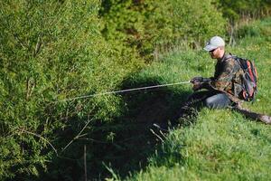 young fisherman fishes near the river. The concept of outdoor activities and fishing photo