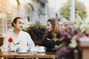 mime guy and girl in cafe drinking coffee. Mime in front of Paris cafe acting like drinking tea or coffee. photo