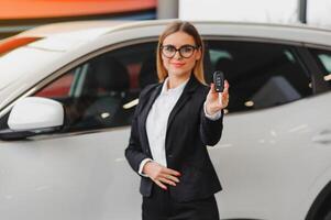 Beautiful young woman buys a car in the dealership saloon. photo