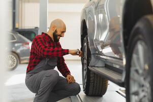 The hand of a car mechanic with a wrench in a combi zone near the car in the workshop photo