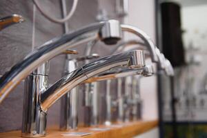 Rows of new faucets in plumbing shop, closeup photo