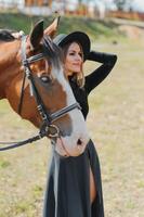 contento de moda joven mujer posando con un caballo en el playa foto