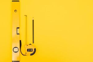 Tools top view on yellow background. Plier, open wrenches, screwdrivers and staple gun flat lay with copy space photo