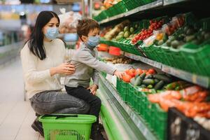 Mom and son wearing protective masks choose fruits to buy in the store. photo