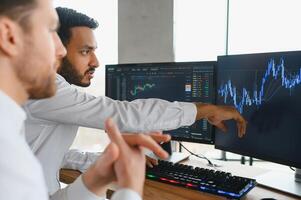 Two diverse crypto traders brokers stock exchange market investors discussing trading charts research reports growth using pc computer looking at screen analyzing invest strategy, financial risks. photo