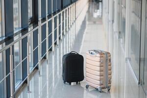 Two suitcases in the airport departure lounge, holidays concept, empty area for copy space or text message, yellow and purple suitcases in empty hall. Travel concept photo