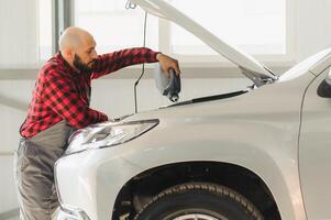 Car mechanic replacing and pouring oil into engine at maintenance repair service station photo