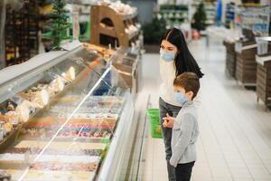 Portrait of a mother and her little son wearing protective face mask at a supermarket during the coronavirus epidemic or flu outbreak. Empty space for text photo