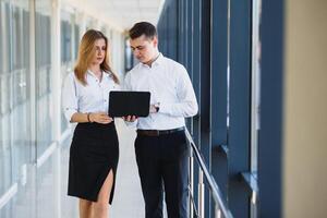 Confident business partners walking down in office building and discussing work photo