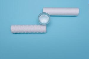 Water filters. Carbon cartridges and a glass on a blue background. Household filtration system. photo