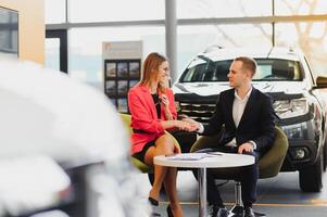 Car dealership sales person at work concept. Portrait of young sales representative wearing formal wear suit, showing vehicles at automobile exhibit center. Close up, copy space, background. photo