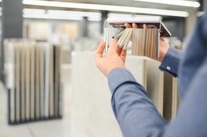 man choosing ceramic tiles and utensils for his home bathroom photo