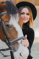 joven mujer fisioterapeuta tomando cuidado un marrón caballo. mujer haciendo un tratamiento en el hombro, cresta, frente, bozal y barbilla ranura. foto