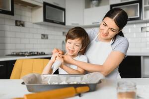 Happy mother and child in kitchen preparing cookies photo