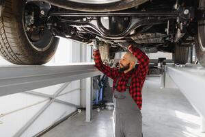 Mechanic working under car at the repair garage. Auto mechanic working in garage. Repair service. photo