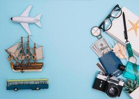 top view travel concept with retro camera films, smartphone, map, passport, compass and Outfit of traveler on blue background with copy space, Tourist essentials, vintage tone effect photo