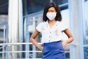 africano americano mujer de negocios vistiendo protector máscara en su cara en el ciudad. el concepto de visitando trabajo durante un pandemia foto